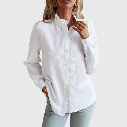 Woman wearing a white button-up shirt and light blue jeans on a plain background